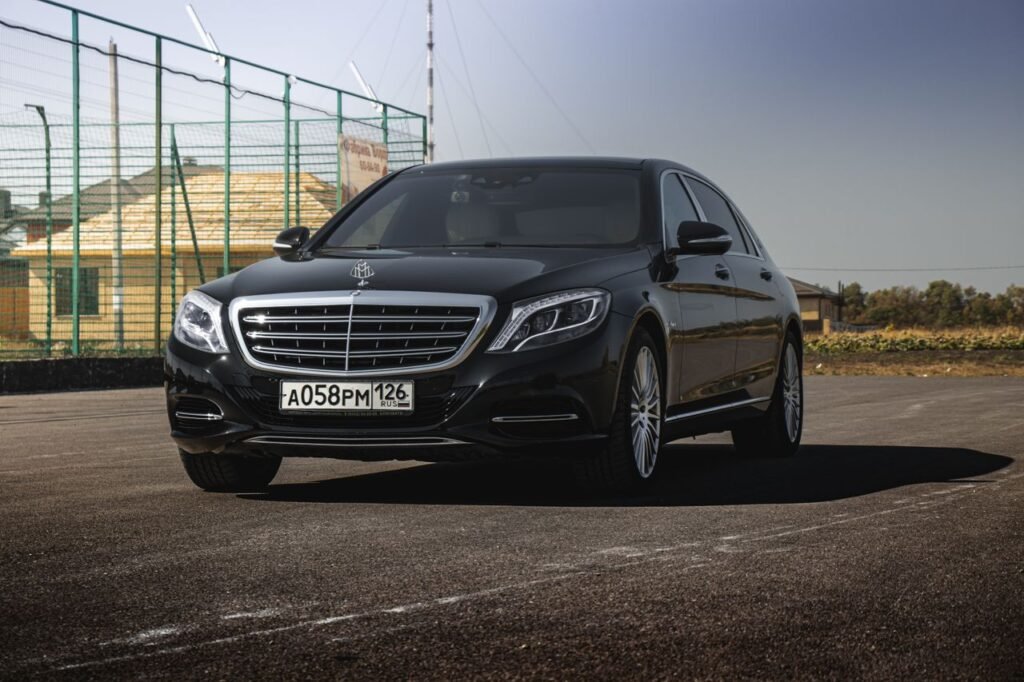 Black Mercedes-Benz Maybach parked on sunny day against clear sky.